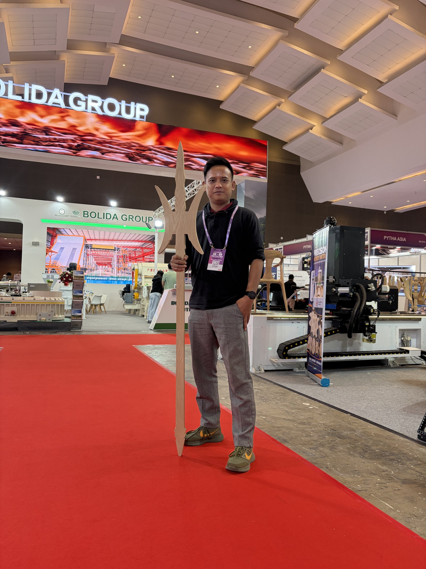 A returning customer poses with a wooden halberd replica cut at the booth.